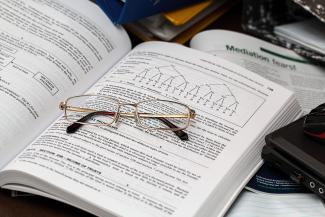 A pair of reading glasses sitting on an open textbook. The book has content on taxes.